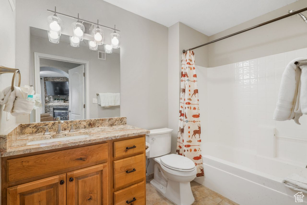 Full bathroom with tile flooring, large vanity, shower / tub combo with curtain, and toilet