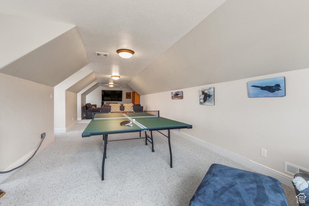 Recreation room with light colored carpet and vaulted ceiling