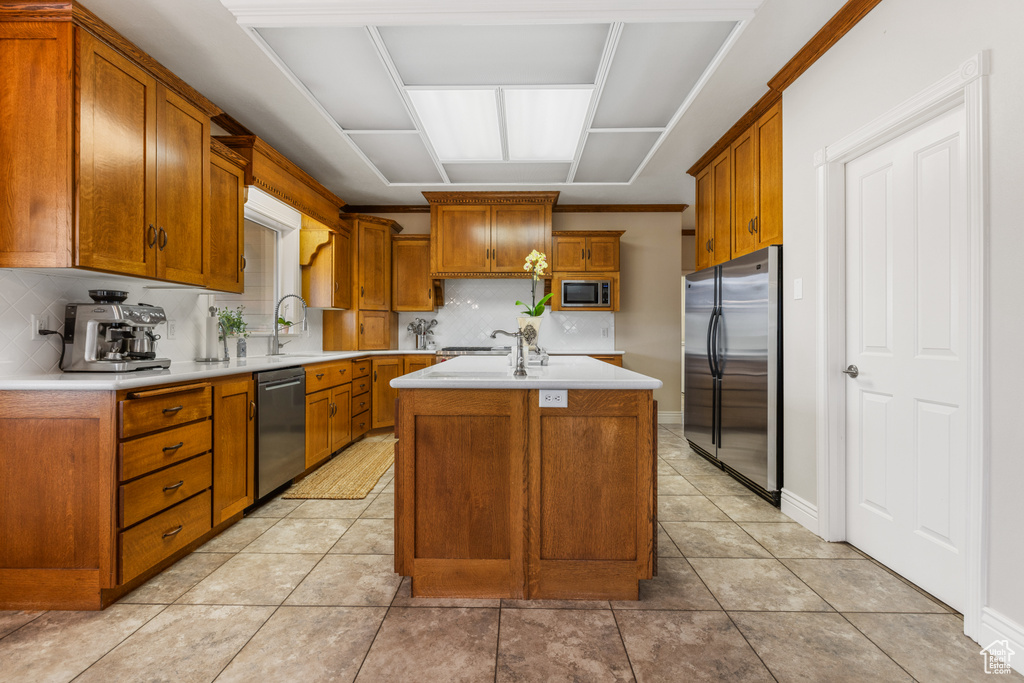 Kitchen with tasteful backsplash, stainless steel appliances, light tile flooring, and a center island
