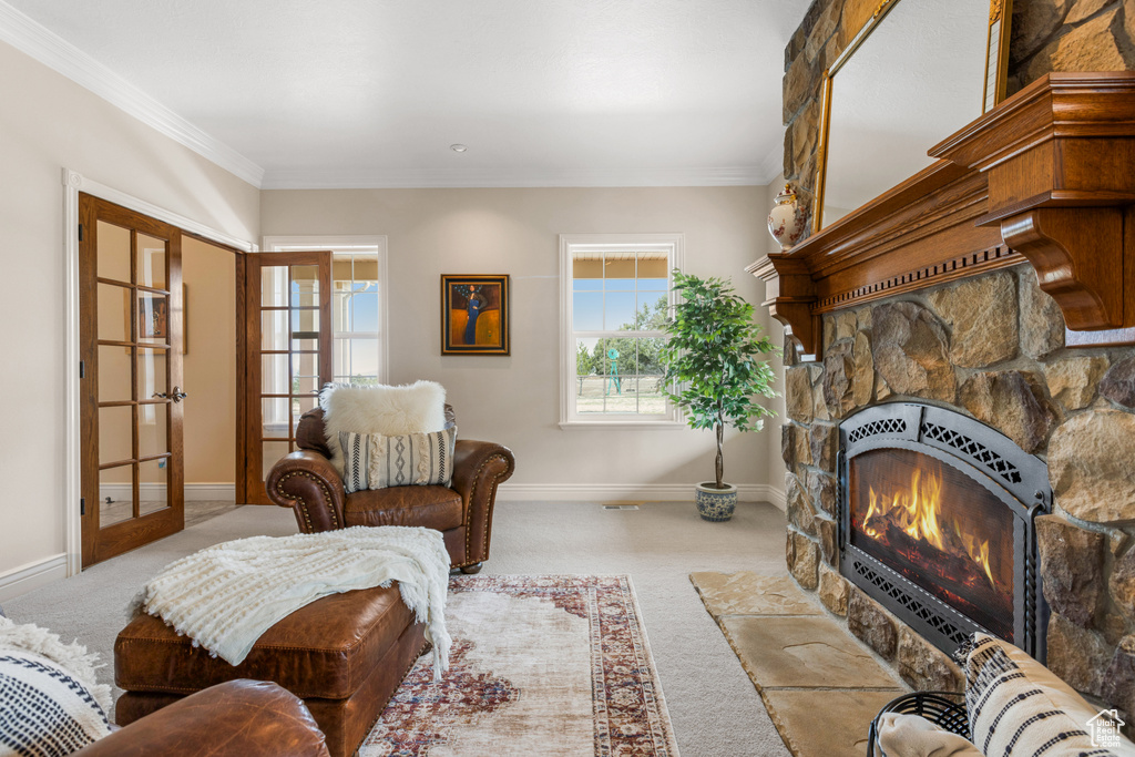 Carpeted living room featuring a stone fireplace, crown molding, and french doors