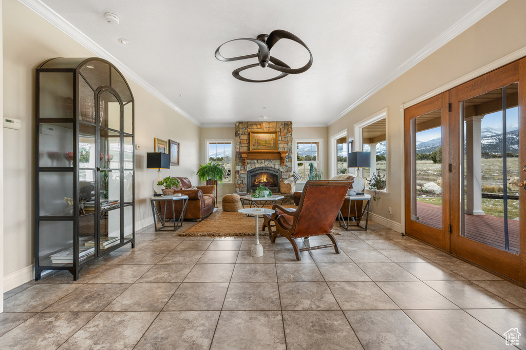 Tiled dining area with a stone fireplace, french doors, and ornamental molding