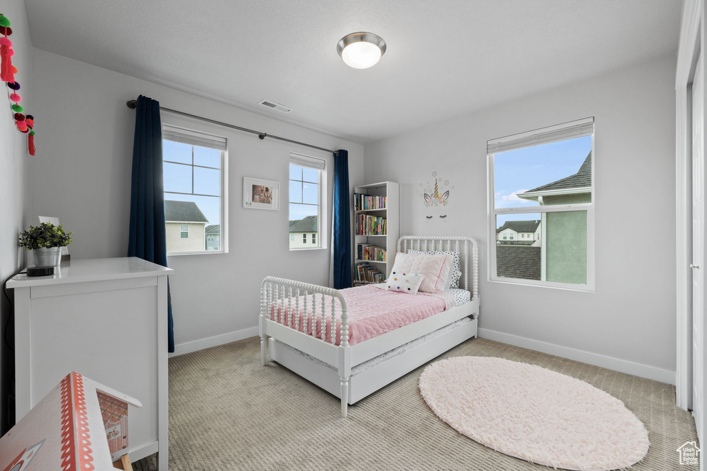 Bedroom featuring light colored carpet and multiple windows