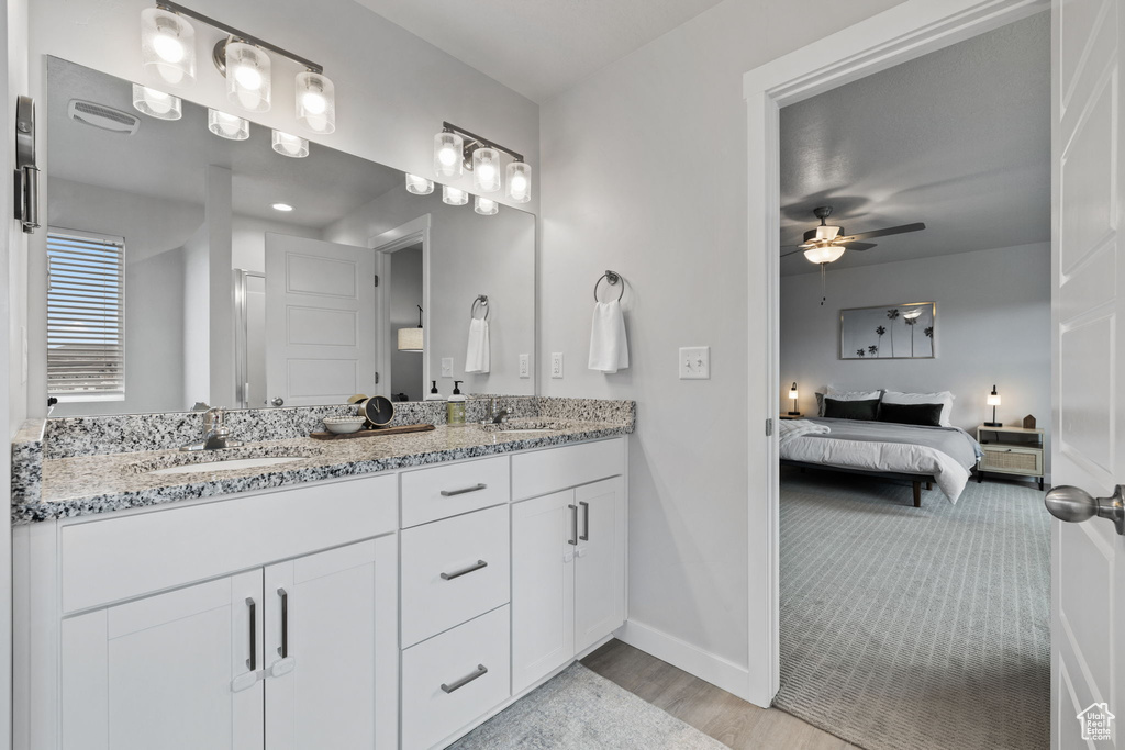 Bathroom featuring vanity with extensive cabinet space, double sink, and ceiling fan
