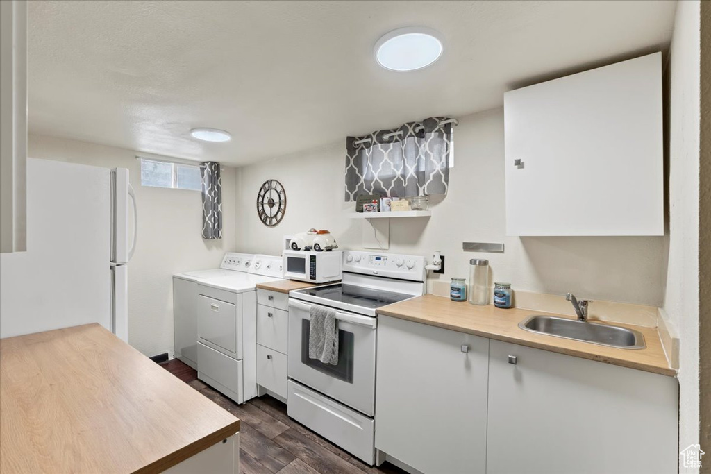 Kitchen featuring white appliances, washer / dryer, white cabinets, dark hardwood / wood-style floors, and sink
