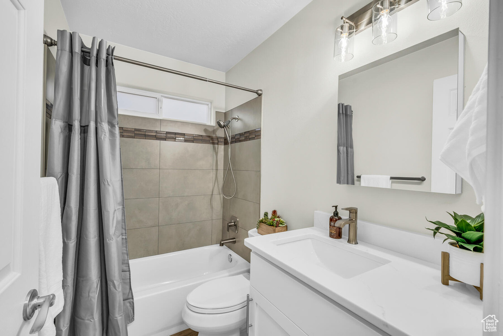 Full bathroom featuring toilet, vanity with extensive cabinet space, and shower / bathtub combination with curtain