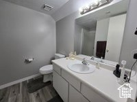 Bathroom with hardwood / wood-style floors, toilet, and large vanity
