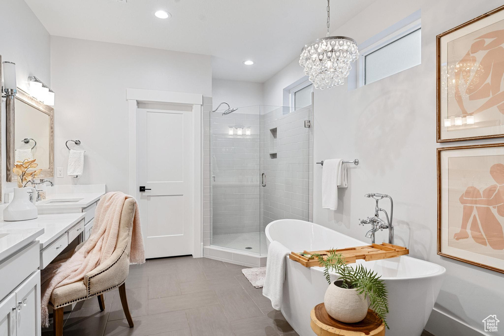 Bathroom with an inviting chandelier, dual vanity, tile floors, and independent shower and bath
