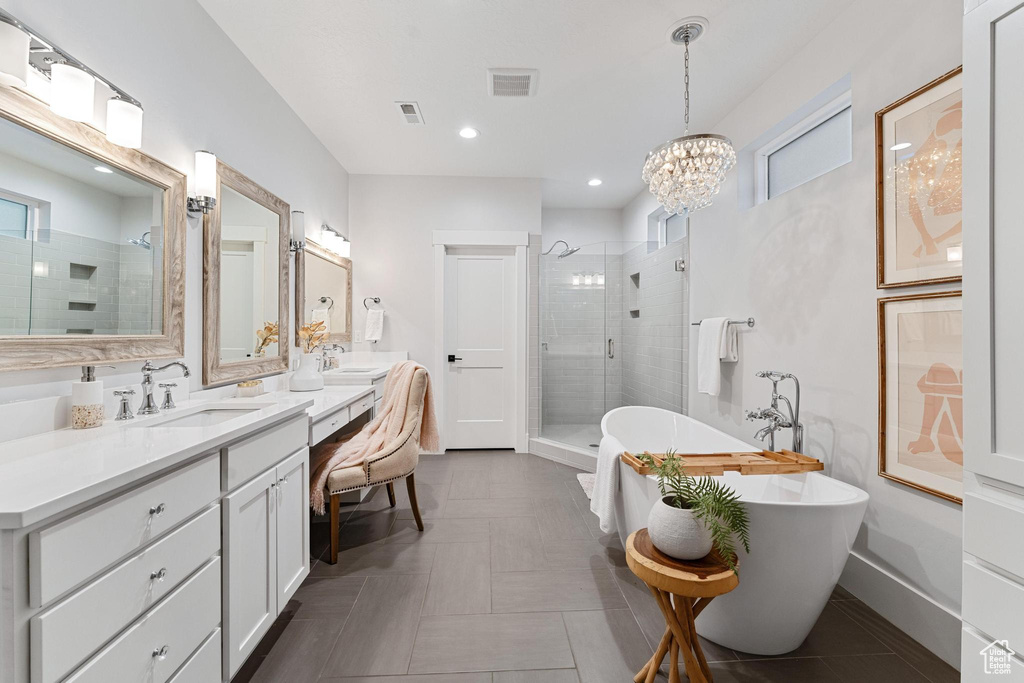 Bathroom featuring a notable chandelier, shower with separate bathtub, tile flooring, and dual vanity