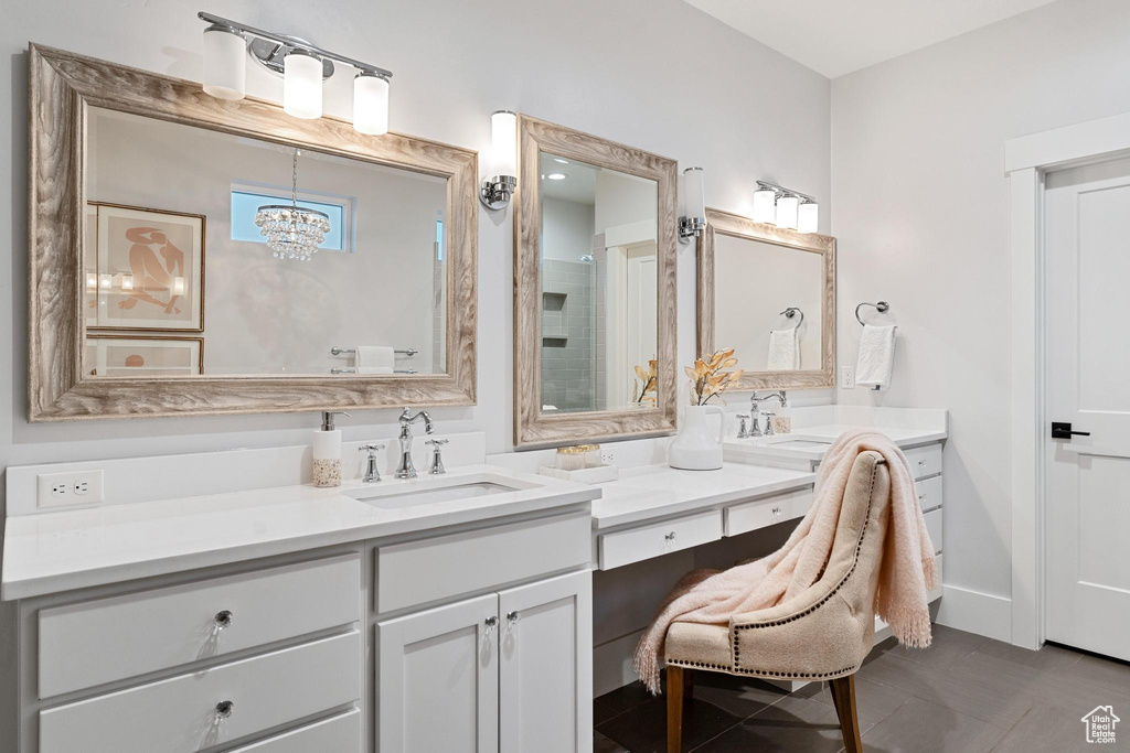 Bathroom featuring a chandelier, dual bowl vanity, and tile floors