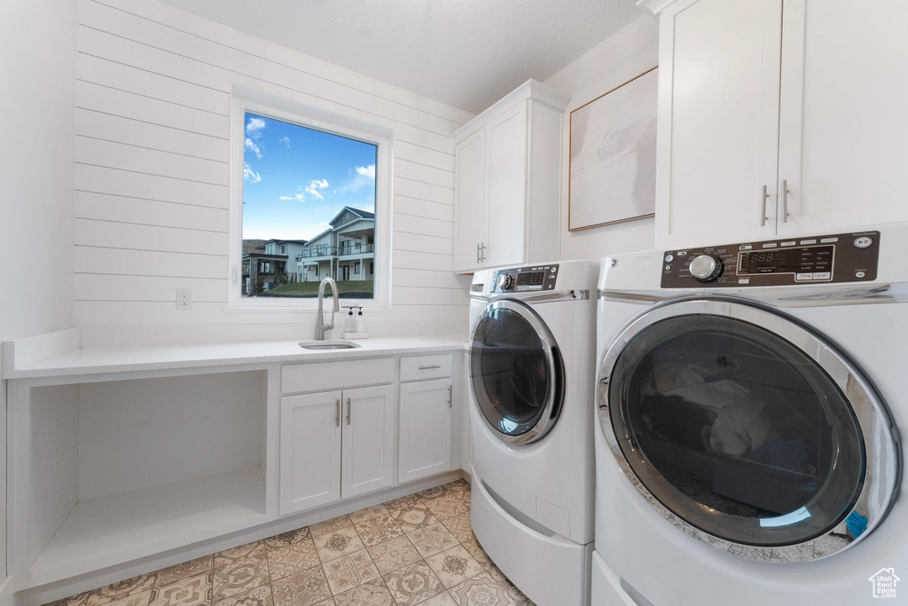 Laundry area featuring cabinets, light tile floors, sink, and washer and clothes dryer
