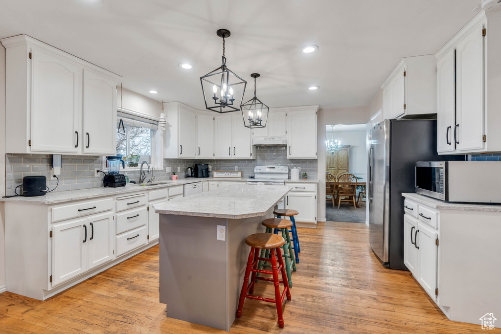 Kitchen featuring light hardwood / wood-style floors, a center island, white cabinetry, and white appliances