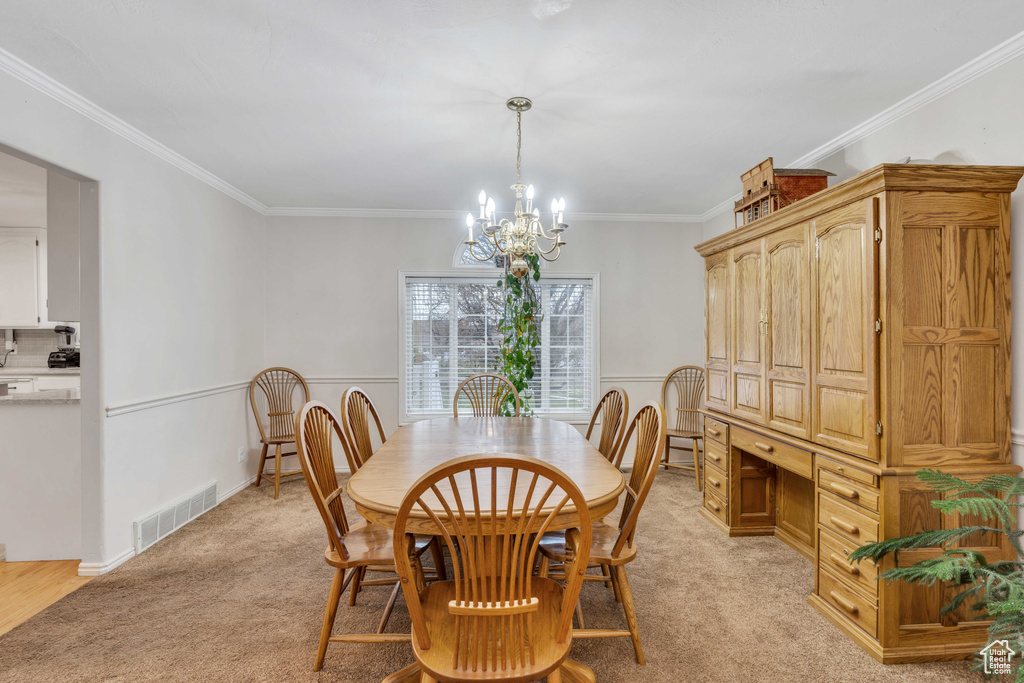 Carpeted dining area with a chandelier and crown molding