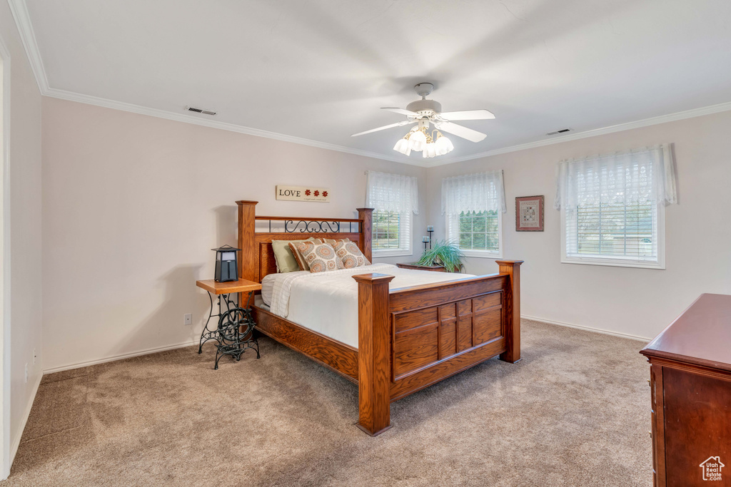 Bedroom with light colored carpet, ceiling fan, and crown molding
