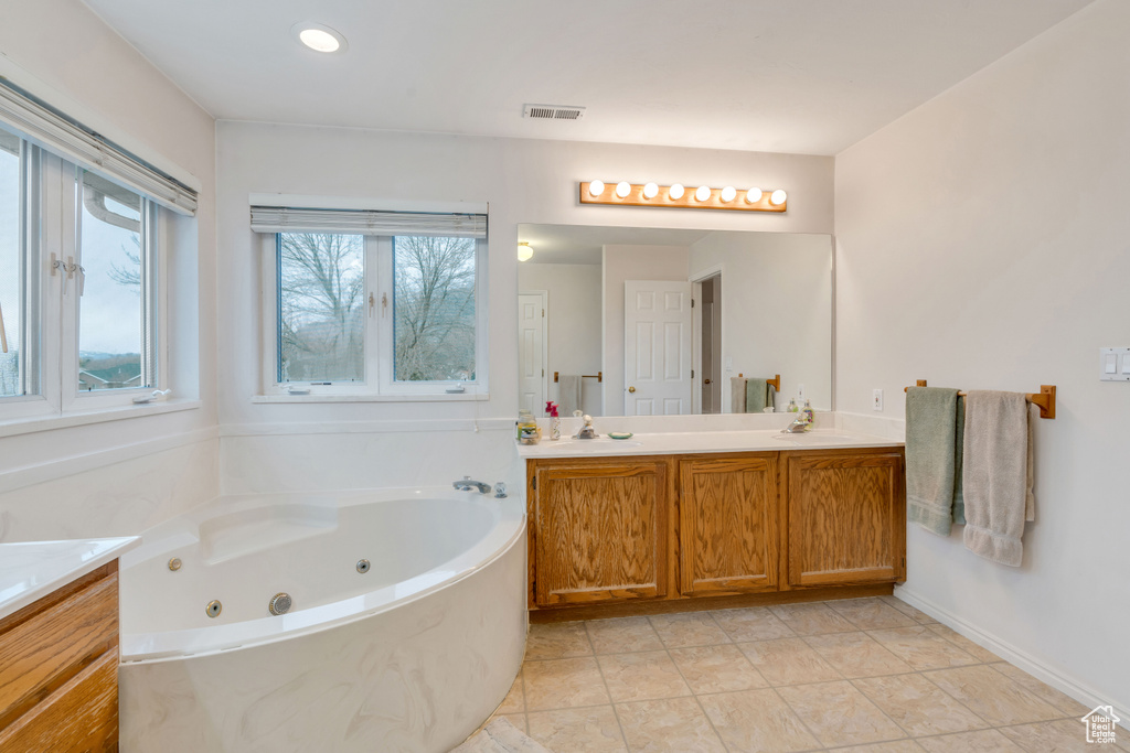 Bathroom with tile floors, a bathing tub, and vanity