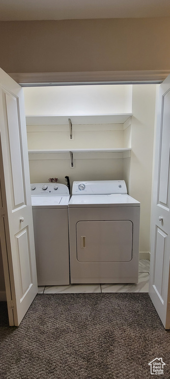 Laundry room with washer and clothes dryer and light colored carpet