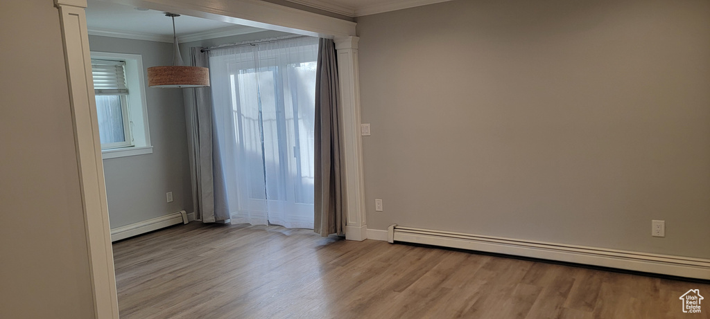 Unfurnished room featuring a baseboard radiator, light wood-type flooring, and crown molding