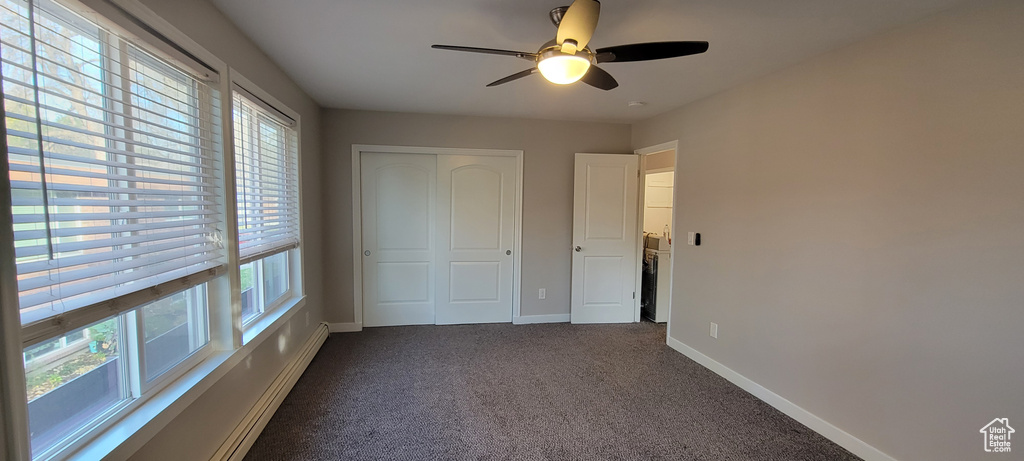 Unfurnished bedroom with a closet, multiple windows, ceiling fan, and dark colored carpet