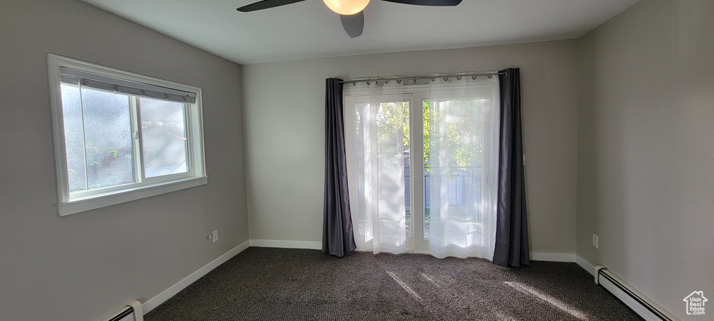 Spare room with ceiling fan, a baseboard radiator, and dark colored carpet