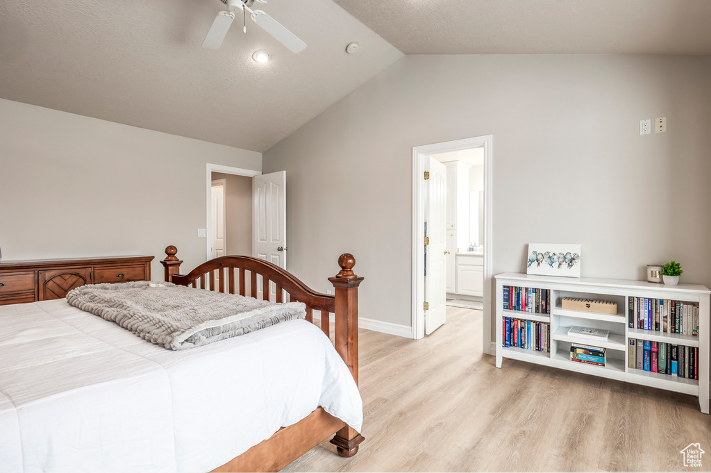 Bedroom featuring ensuite bathroom, vaulted ceiling, ceiling fan, and light hardwood / wood-style flooring