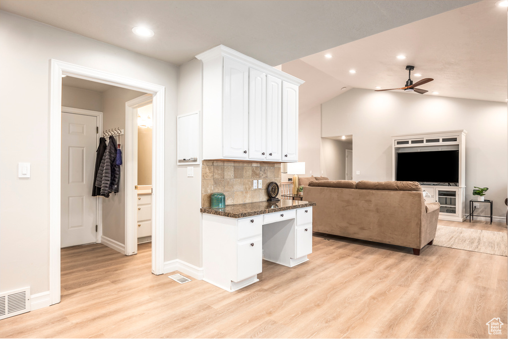 Kitchen featuring light hardwood / wood-style floors, ceiling fan, tasteful backsplash, white cabinetry, and dark stone countertops