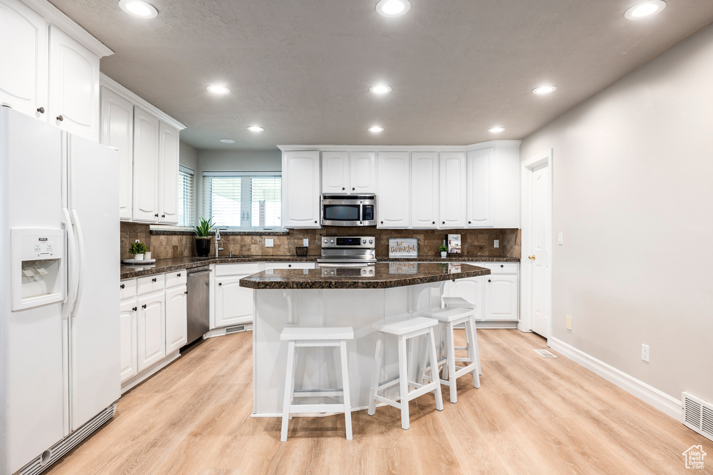 Kitchen with a kitchen island, appliances with stainless steel finishes, and white cabinetry