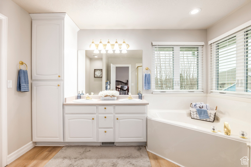 Bathroom featuring a tub, double vanity, and hardwood / wood-style flooring