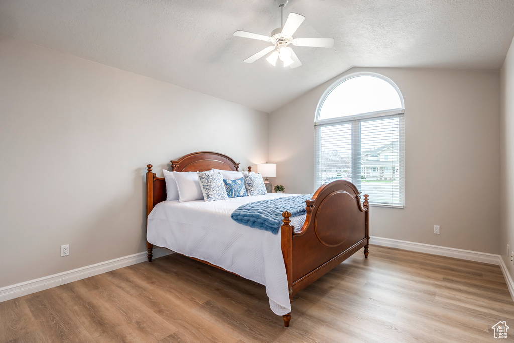 Bedroom featuring a textured ceiling, ceiling fan, vaulted ceiling, and light wood-type flooring