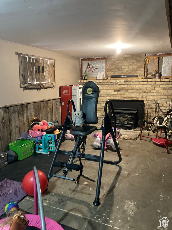 Workout room with brick wall, concrete flooring, and a brick fireplace