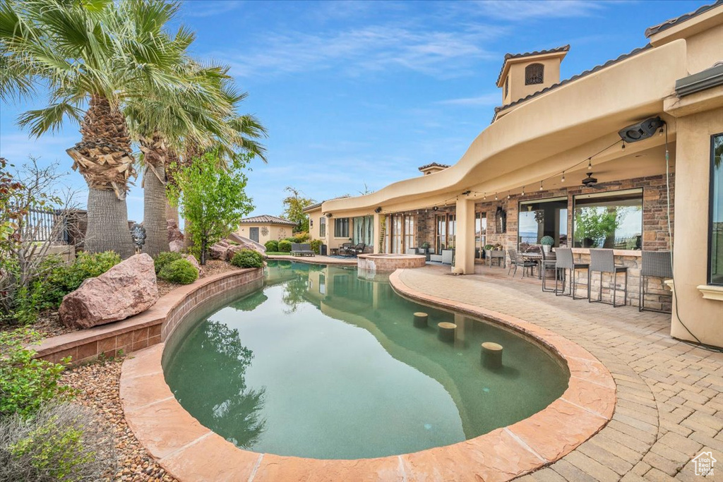 View of pool with exterior bar, ceiling fan, and a patio