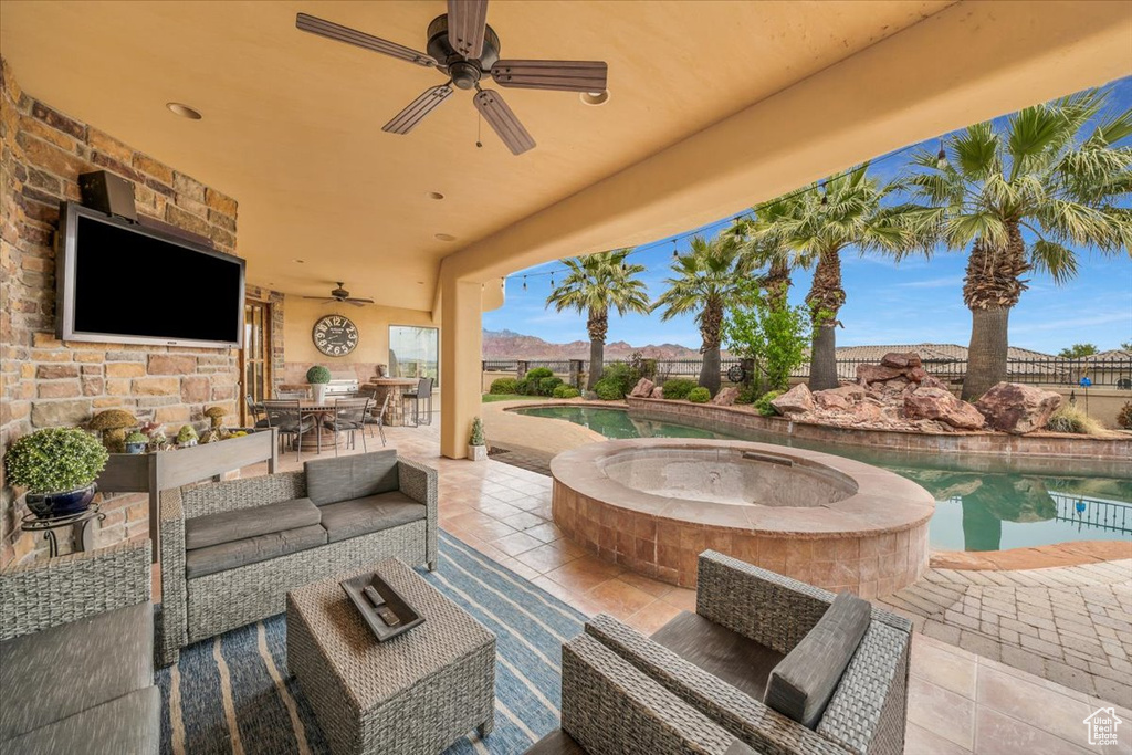 View of patio featuring a swimming pool with hot tub, an outdoor living space with a fireplace, and ceiling fan