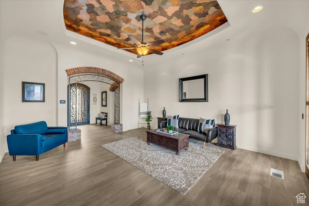 Living room featuring a tray ceiling, hardwood / wood-style floors, and ceiling fan