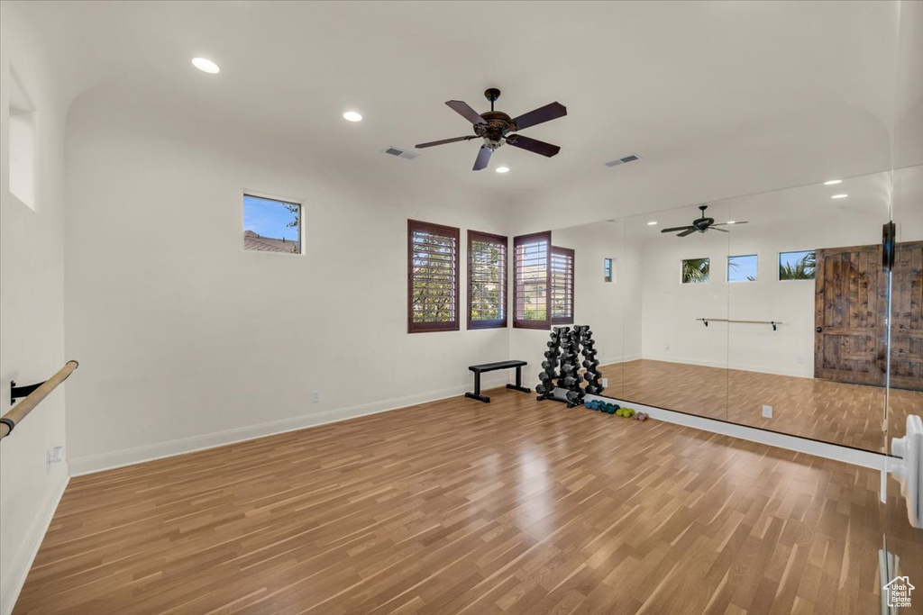 Workout area featuring a barn door, ceiling fan, and light wood-type flooring