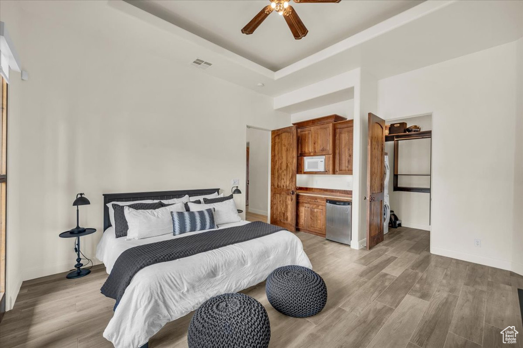 Bedroom featuring ceiling fan, a tray ceiling, and light hardwood / wood-style flooring