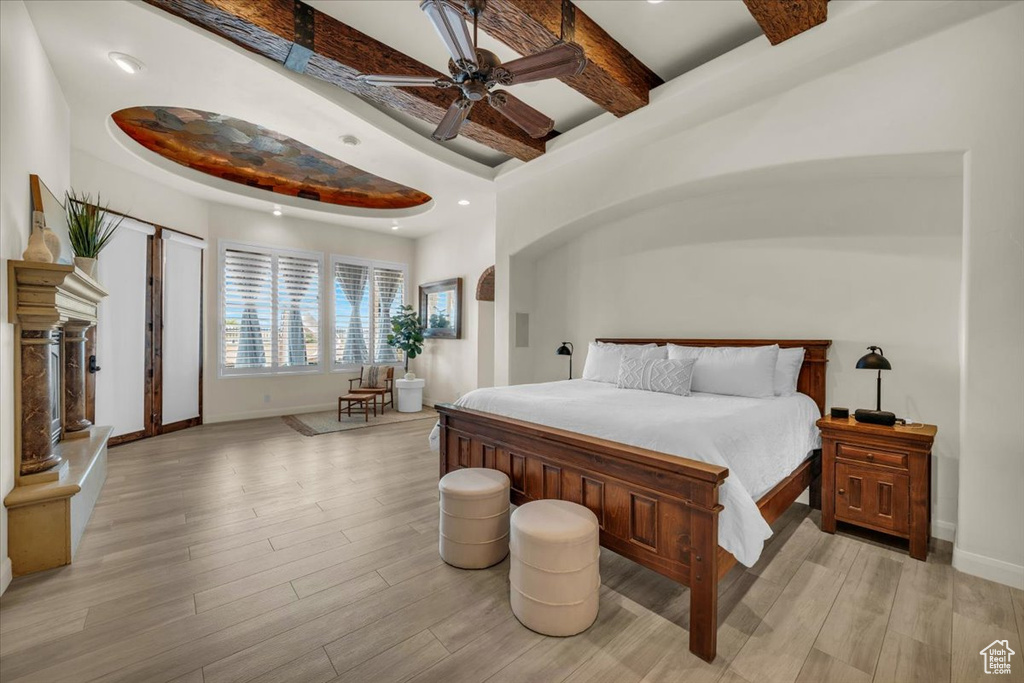 Bedroom with a raised ceiling, ceiling fan, and light wood-type flooring