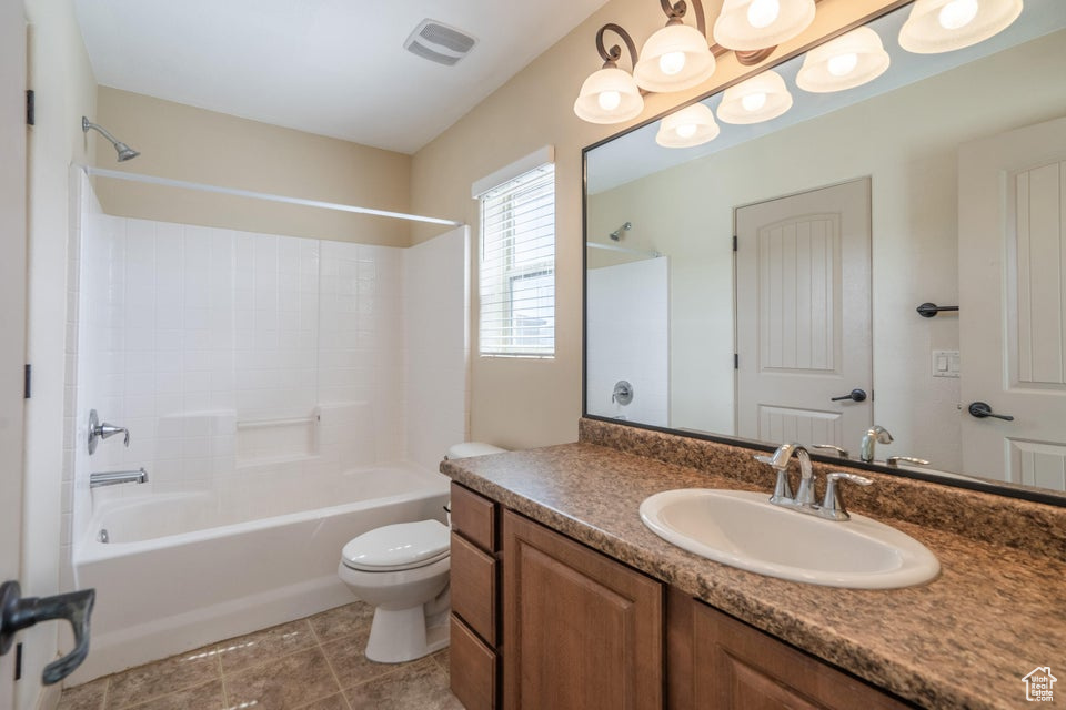 Full bathroom with toilet, tile flooring, vanity, and shower / tub combination