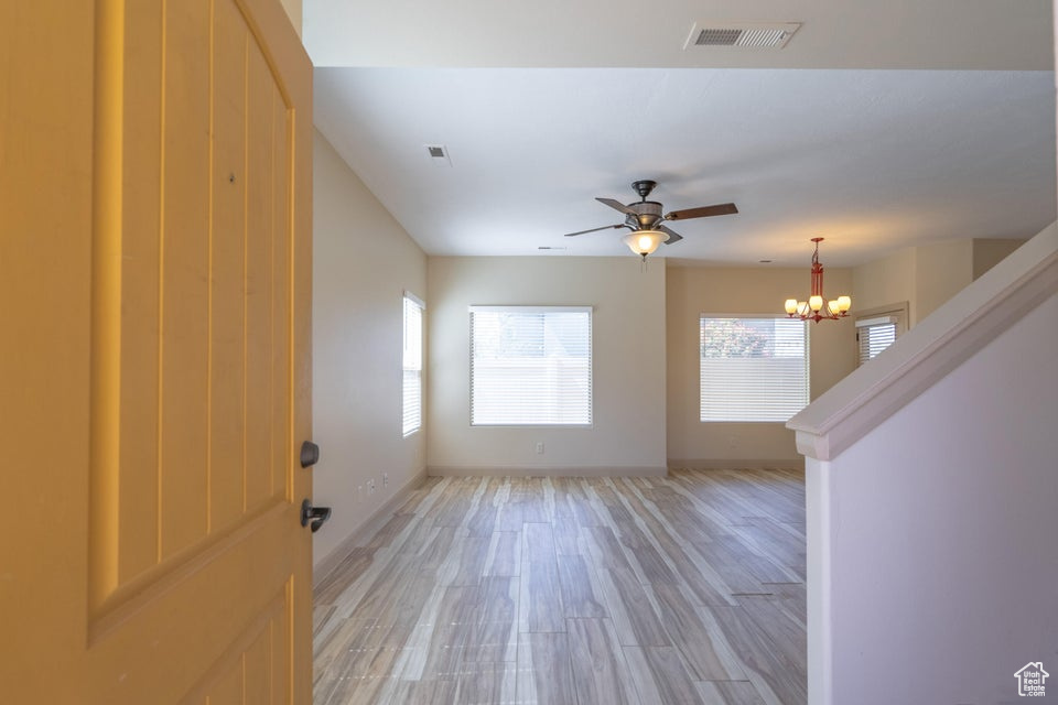 Spare room featuring light hardwood / wood-style floors and ceiling fan with notable chandelier