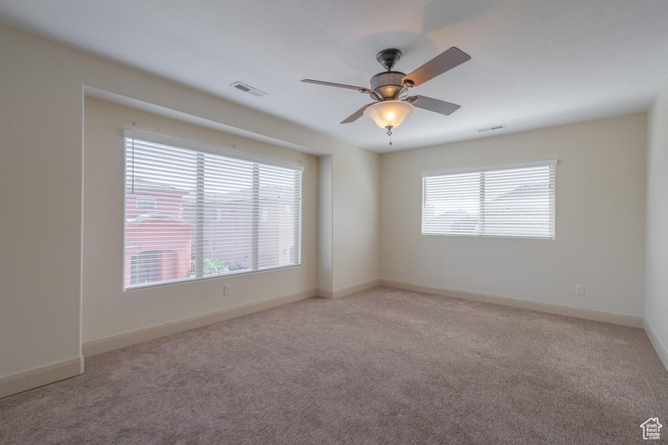 Unfurnished room featuring light carpet, a healthy amount of sunlight, and ceiling fan