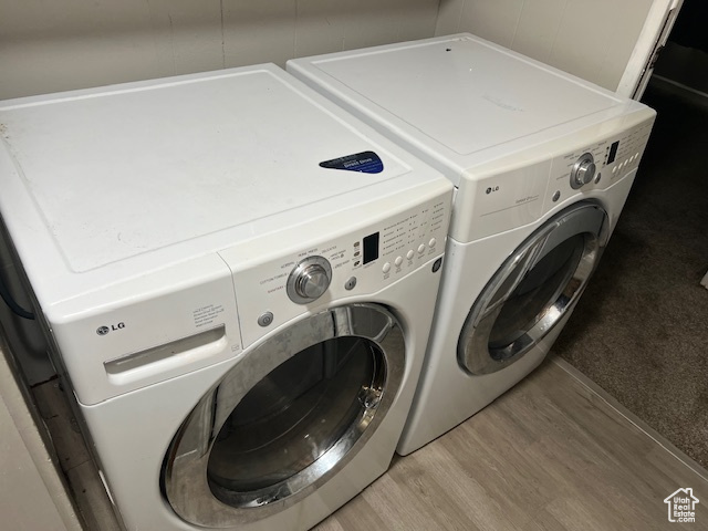 Clothes washing area featuring washer and clothes dryer and light hardwood / wood-style flooring
