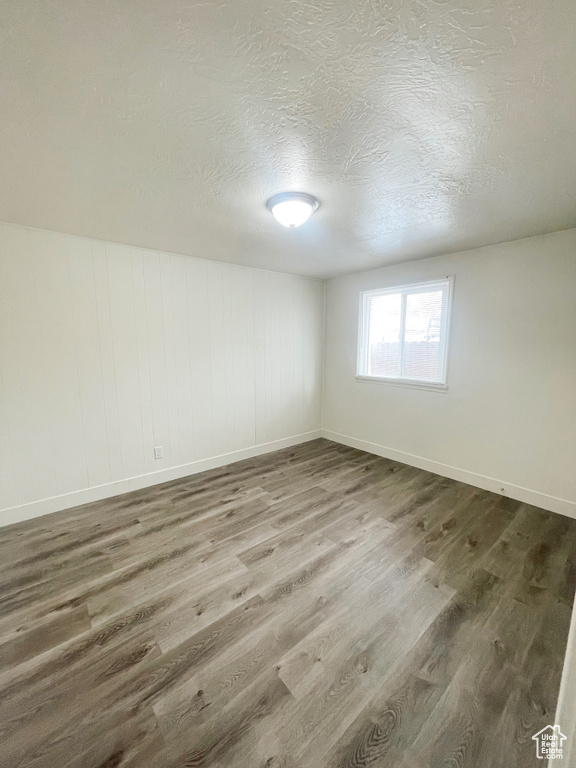 Empty room featuring dark wood-type flooring and a textured ceiling