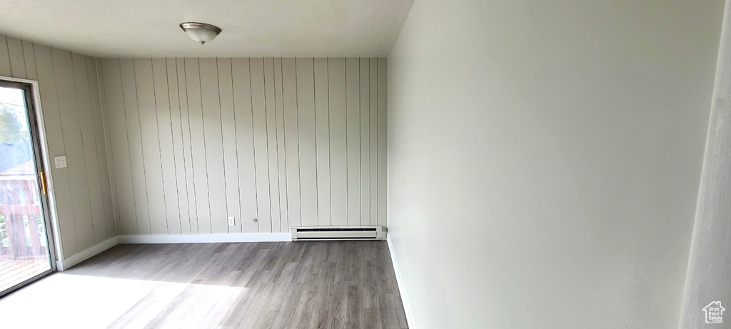 Empty room featuring hardwood / wood-style floors and baseboard heating