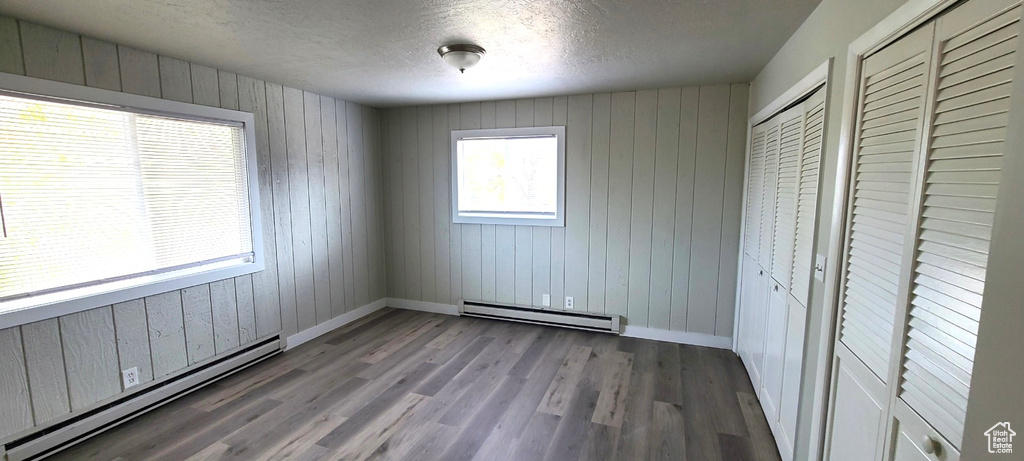 Unfurnished bedroom featuring a textured ceiling, a baseboard radiator, and wood-type flooring