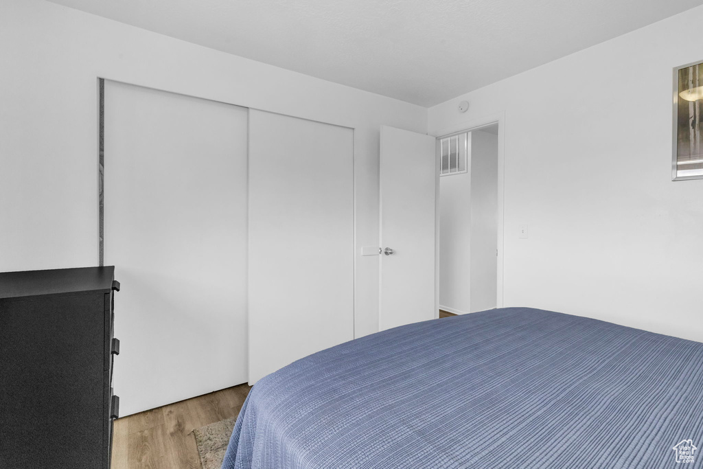 Bedroom with light hardwood / wood-style floors and a closet