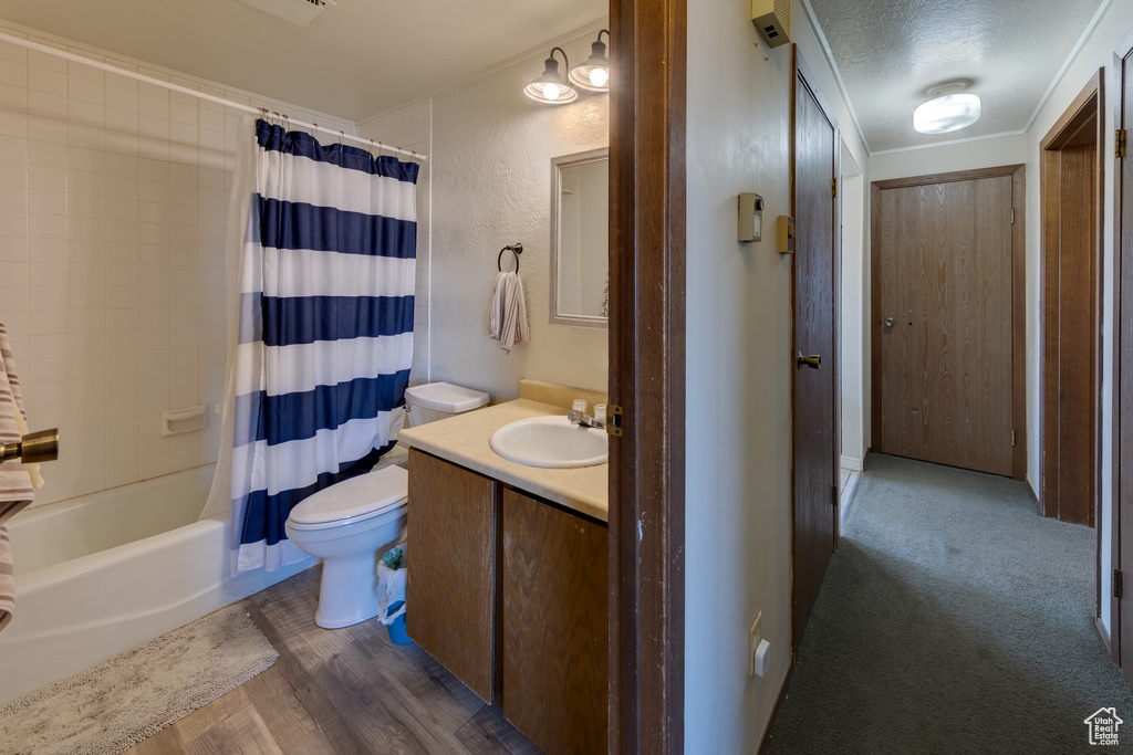 Full bathroom with shower / bath combo, toilet, wood-type flooring, a textured ceiling, and vanity