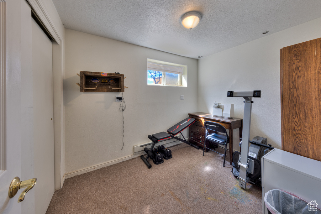 Workout room with a textured ceiling, carpet flooring, and baseboard heating