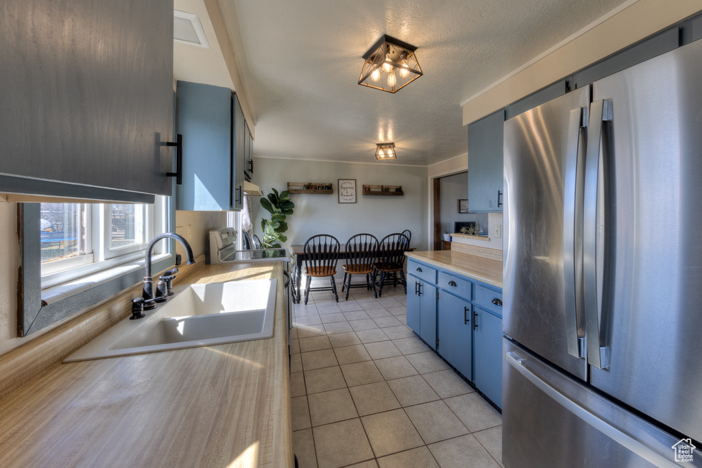 Kitchen with stainless steel refrigerator, light tile flooring, and sink