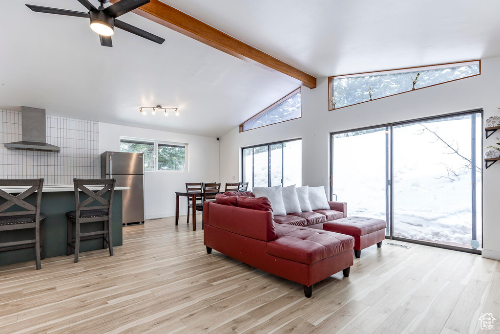 Living room featuring high vaulted ceiling, light hardwood / wood-style floors, and ceiling fan