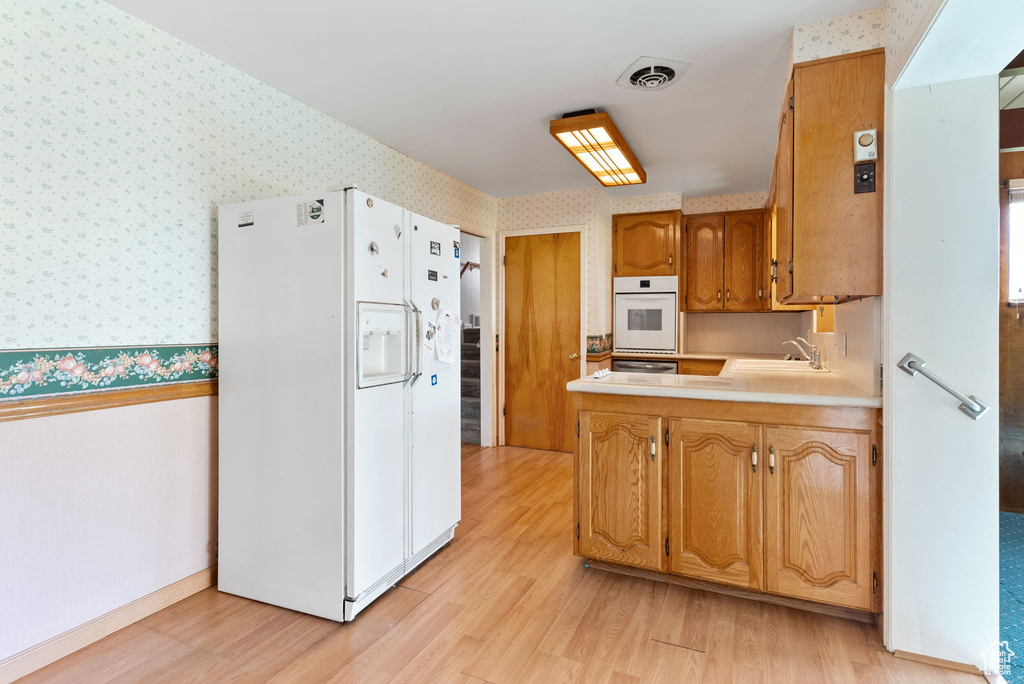 Kitchen featuring sink, white appliances, and light wood-type flooring