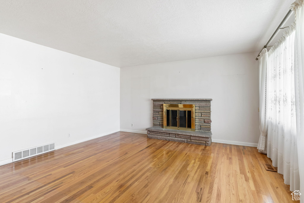 Unfurnished living room with light hardwood / wood-style flooring and a stone fireplace