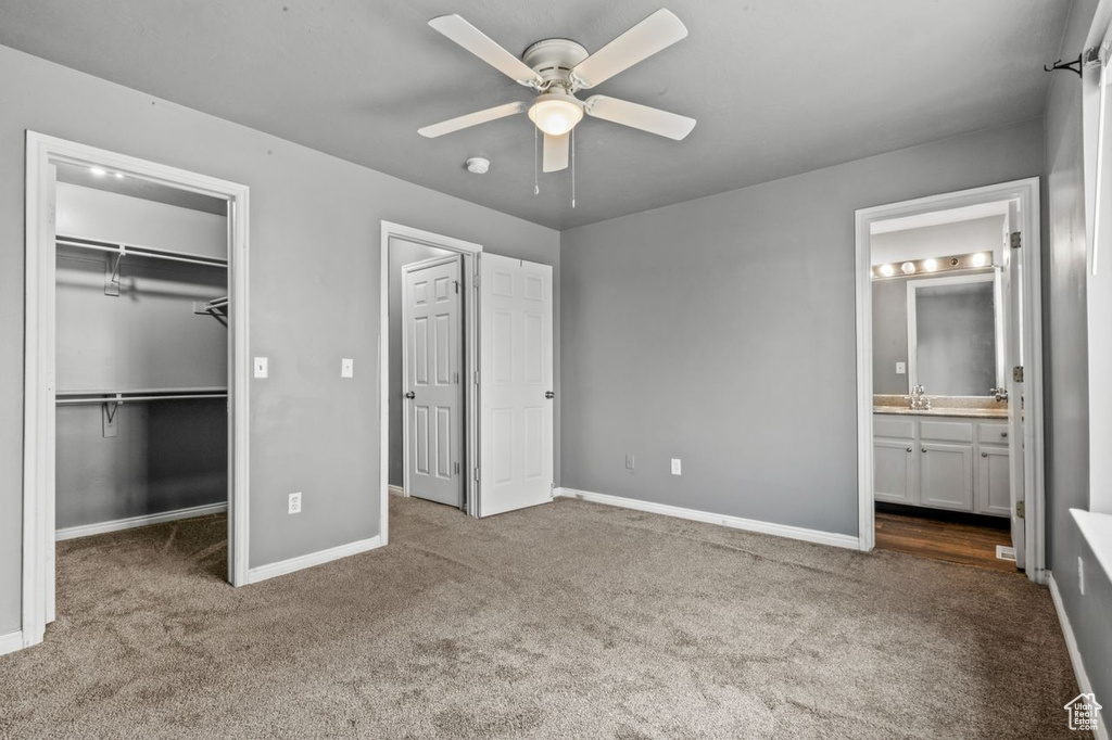 Unfurnished bedroom with ceiling fan, sink, light carpet, a spacious closet, and ensuite bathroom