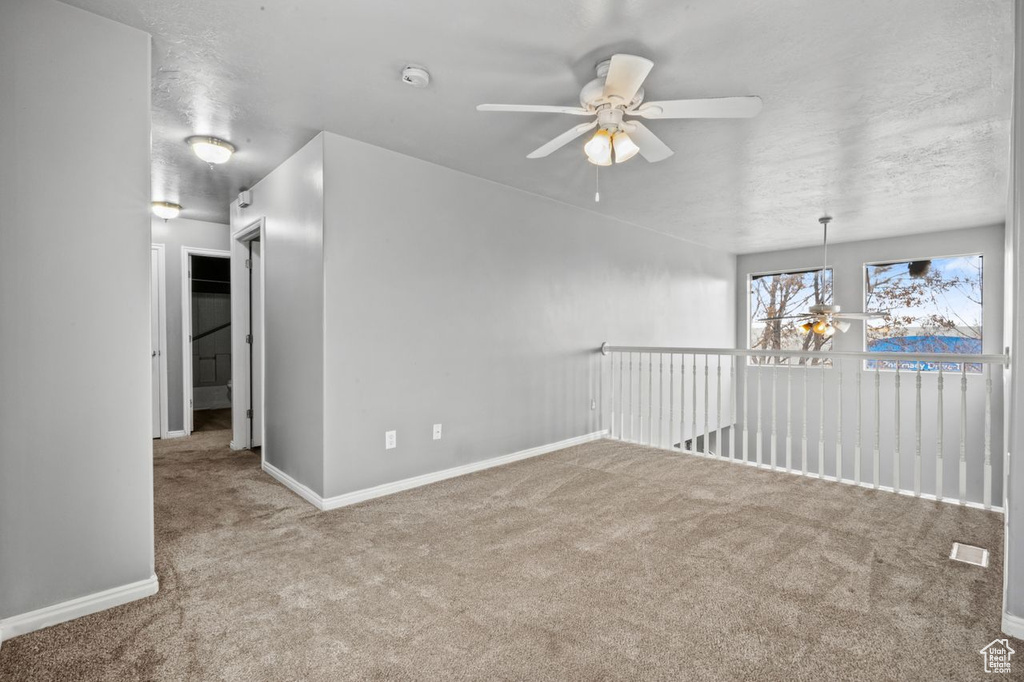 Spare room featuring light carpet and ceiling fan with notable chandelier